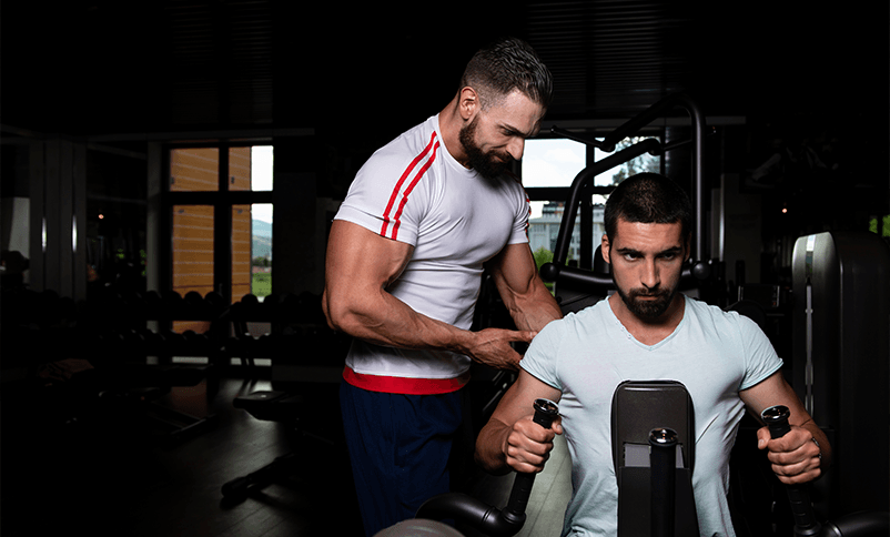 Personal trainer guiding a client through a seated machine exercise